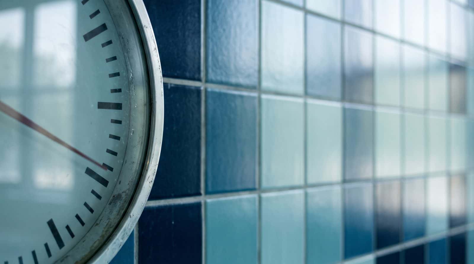 Pool wall clock beside a blue tiled wall