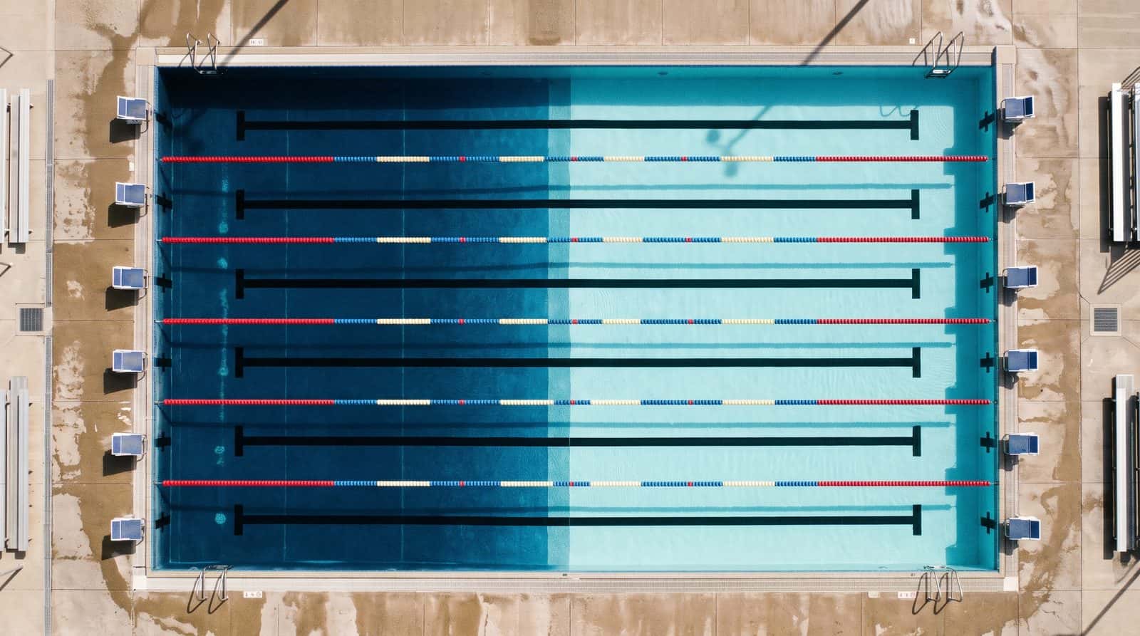 Overhead view of a pool with lane ropes and starting blocks