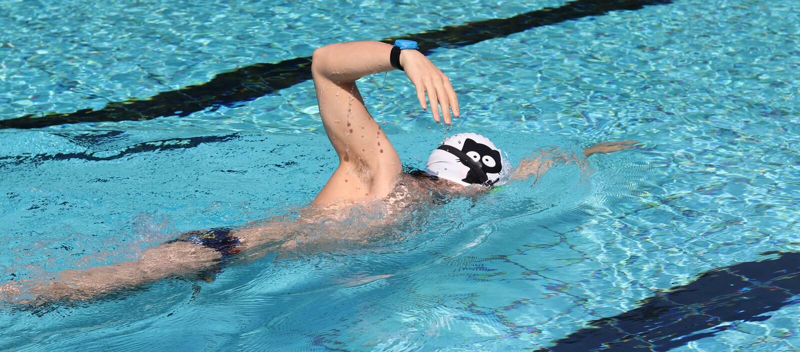 SwimSensei sensor being strapped to a swimmer's ankle at the pool edge
